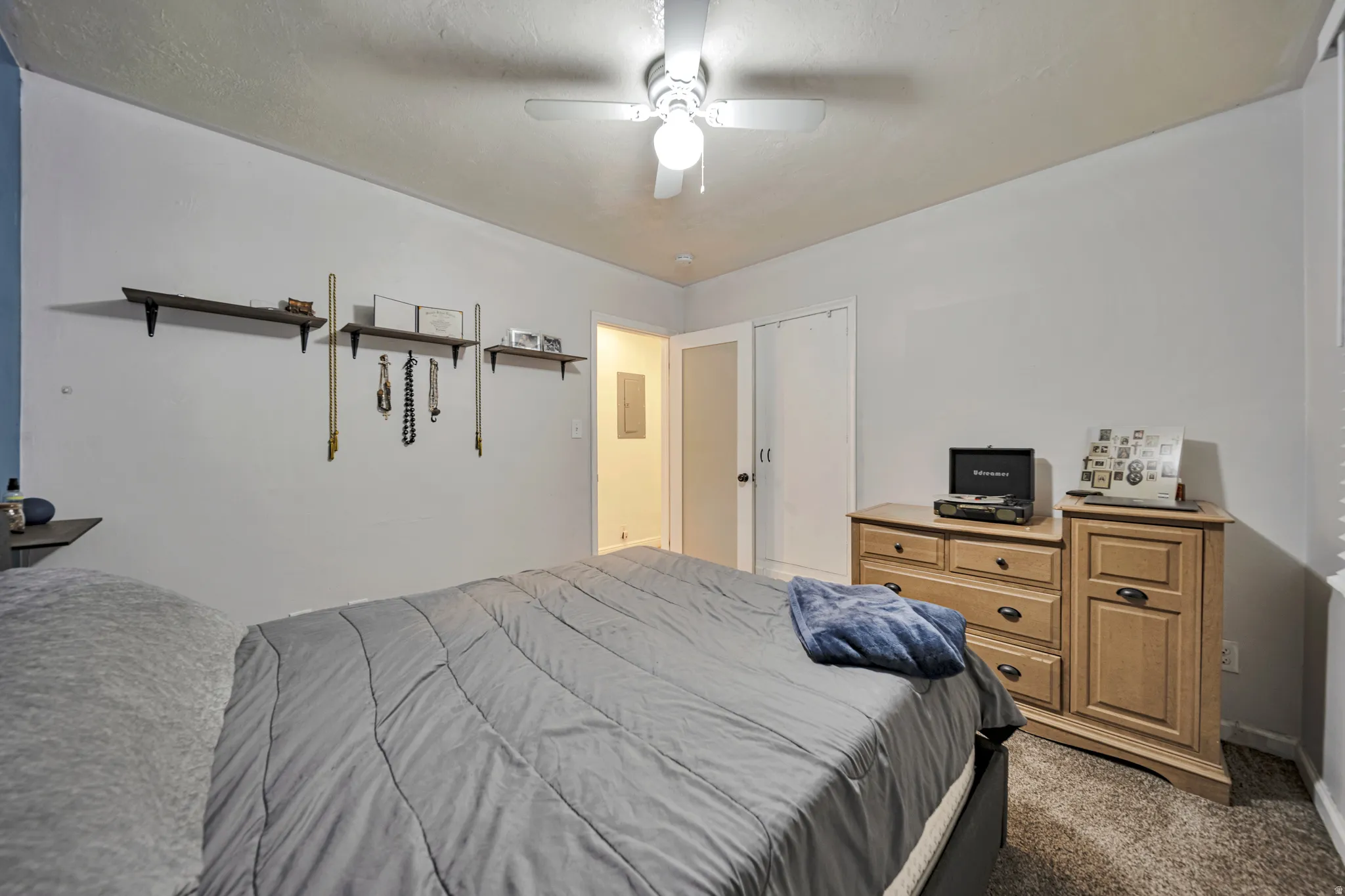 Bedroom featuring light-colored walls, ceiling fan with integrated lighting, built-in shelving, carpet flooring, and a closet with bi-fold doors