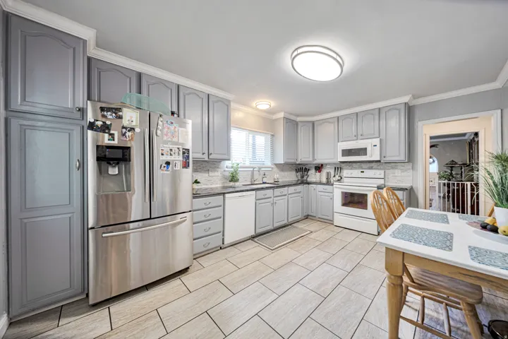 Kitchen featuring gray cabinetry, light-toned tile flooring, and a patterned tile backsplash