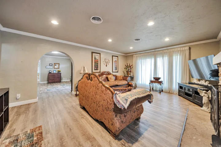 Living area featuring wood-finish flooring, recessed lighting, and a prominent arched entryway