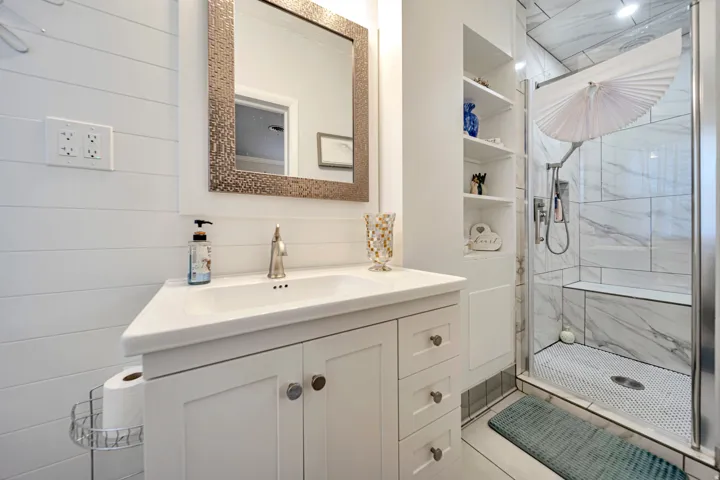 Bathroom featuring a modern vanity with integrated sink, shiplap wall accents, and a walk-in shower