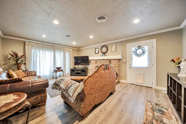 Living area featuring wood-finish flooring, recessed lighting, and a stone-faced fireplace with a substantial mantel
