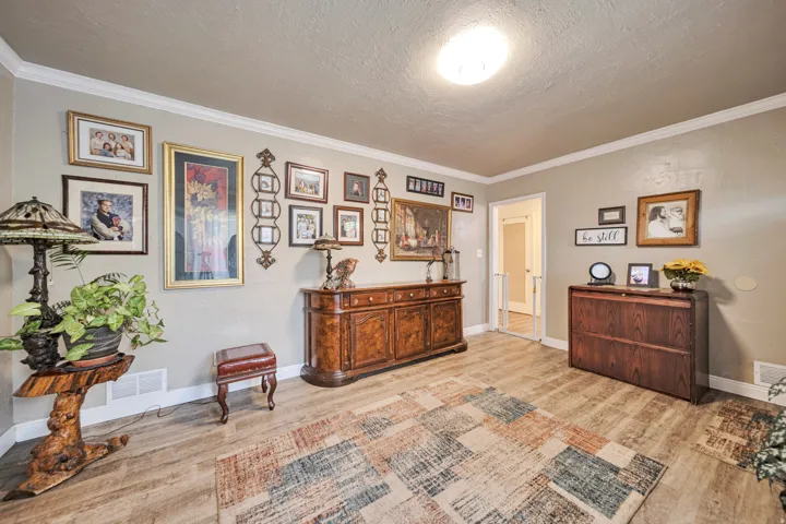 Light wood-finish flooring complements the neutral wall color in this room featuring crown molding and baseboards