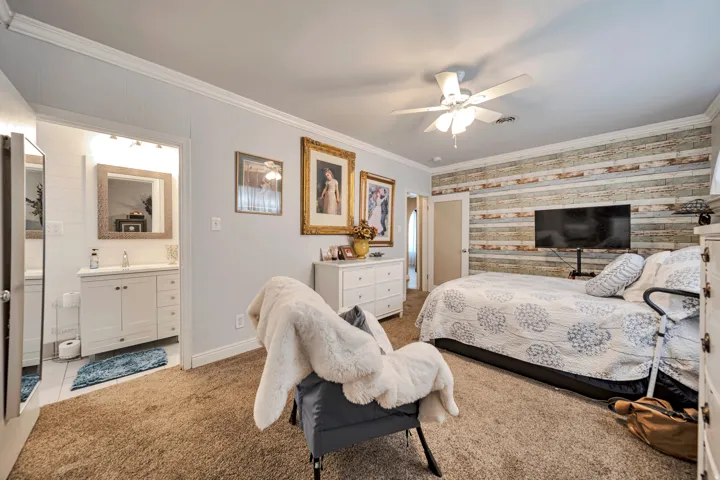 Spacious room featuring a decorative wood plank accent wall, plush carpet flooring, and a ceiling fan with integrated lighting