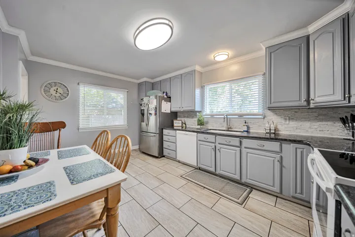 Kitchen featuring gray cabinetry, dark countertops, and a white subway tile backsplash