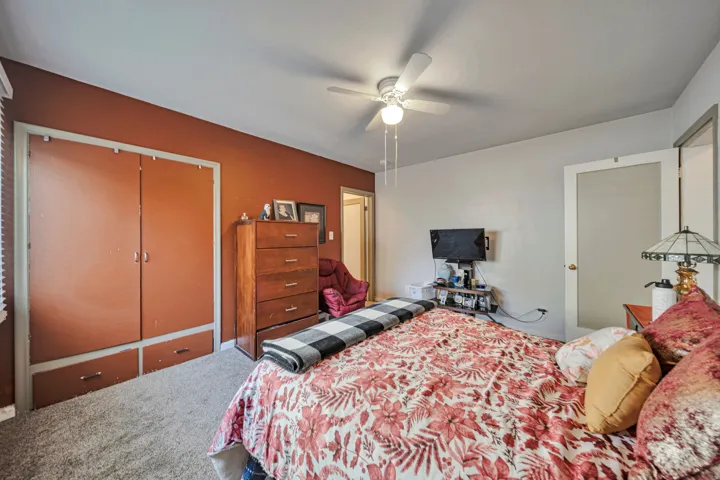 Bedroom featuring wall-to-wall carpeting, a built-in closet with integrated drawer storage, and a ceiling fan with integrated lighting