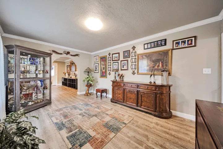 Spacious interior featuring wood-finish flooring, crown molding, and an arched doorway
