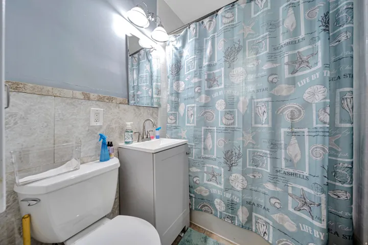 Bathroom featuring a subway-tiled shower enclosure, single vanity with a basin sink, and a wall-mounted light fixture