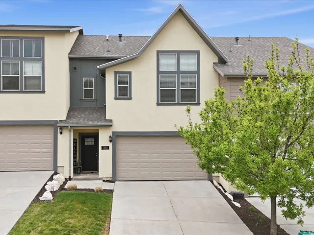 Contemporary multi-level townhome featuring a neutral stucco exterior with dark trim