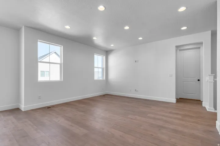 Spacious room featuring wood-finish flooring, recessed lighting, and multiple windows