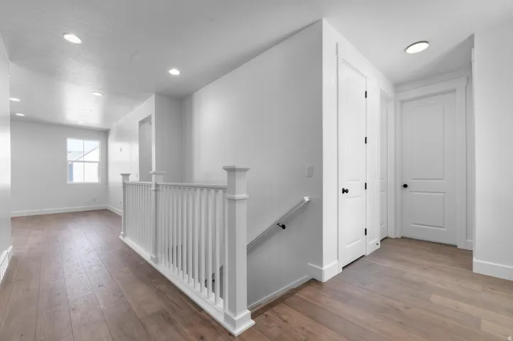 Hardwood-finish flooring, recessed lighting, white panel doors, and a white baluster railing