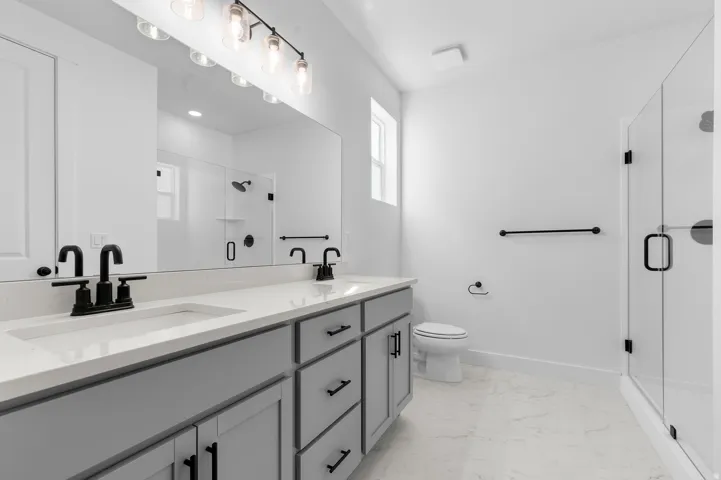 Dual vanity with matte black fixtures, light gray cabinetry, and quartz countertops