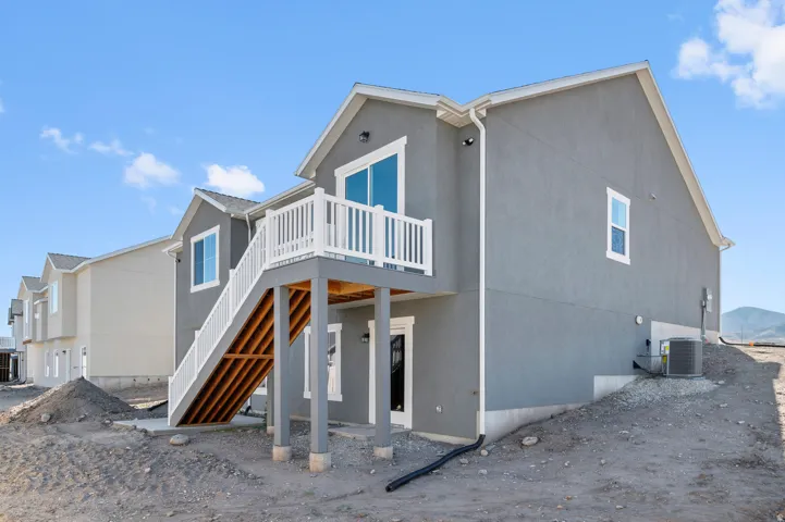 Contemporary stucco exterior with a second-story balcony and ground-level patio access