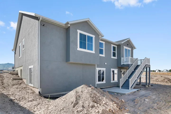 Stucco exterior with multiple windows, second-story balcony with white railing, and exterior staircase