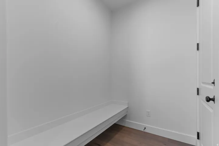 Built-in bench seating, wood-finish flooring, white walls, white trim, paneled door with dark hardware