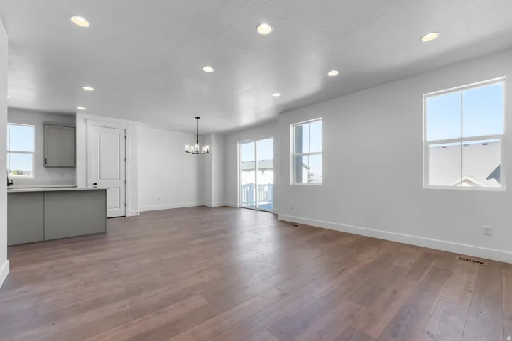 Wood-finish flooring, recessed lighting, matte gray cabinetry, white countertops, and a contemporary chandelier