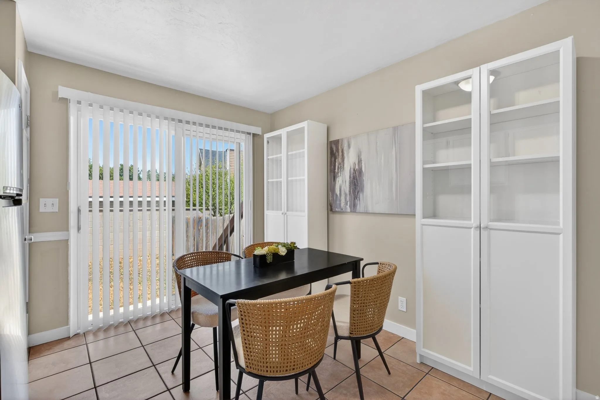 Dining area featuring tile flooring, a sliding glass door, and built-in white cabinetry with glass-front uppers
