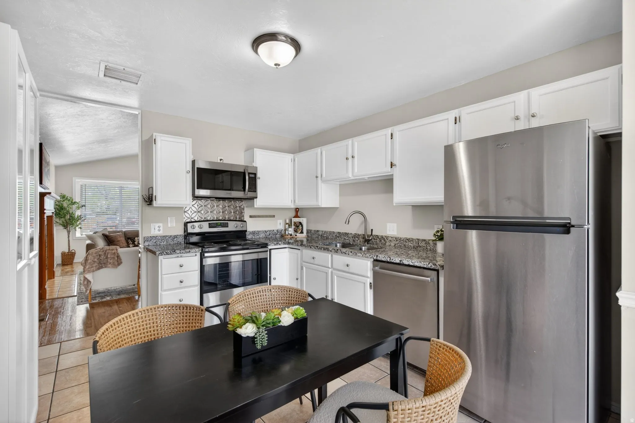 Kitchen featuring white cabinetry, stainless steel appliances, granite countertops, and a decorative tile backsplash