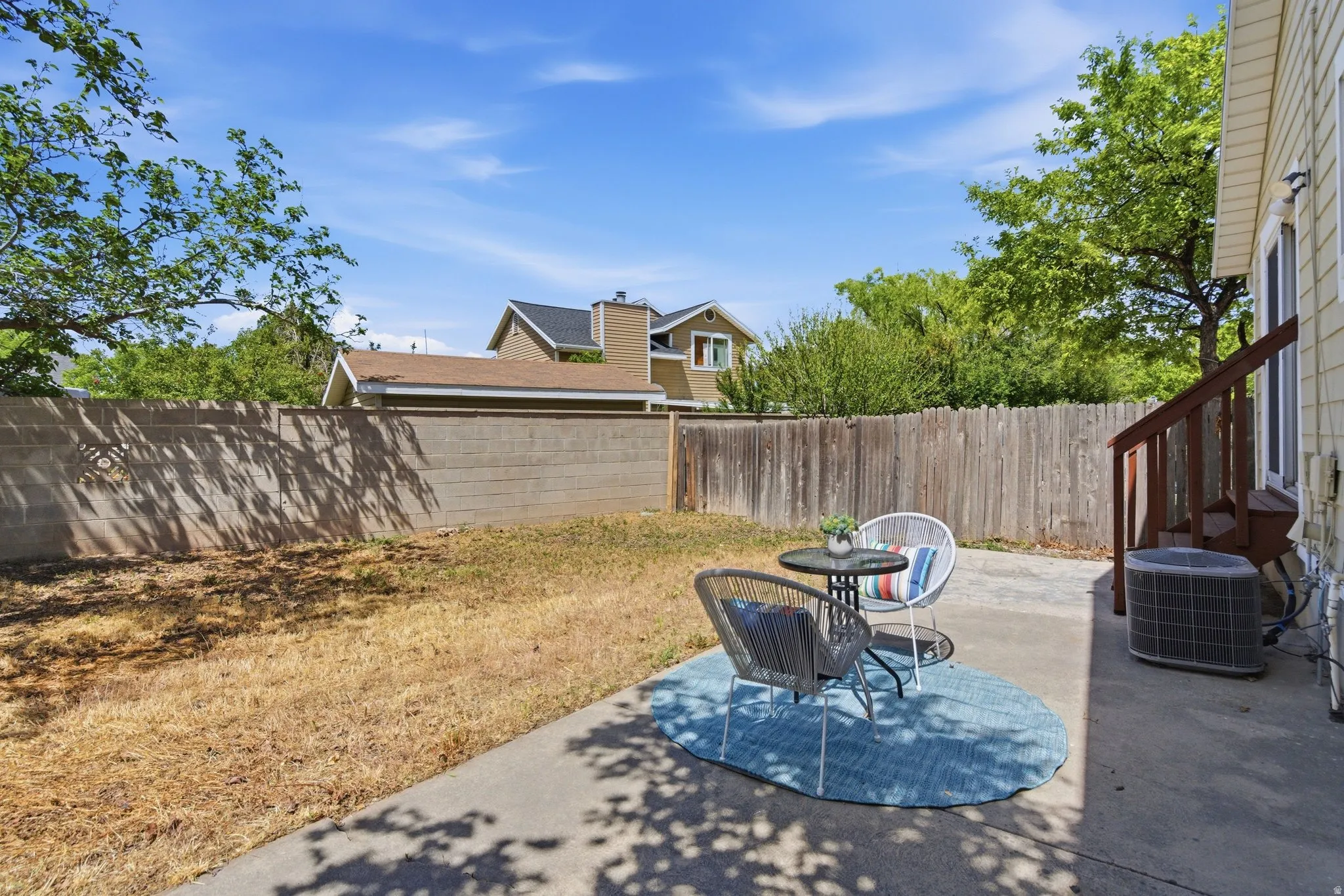 Expansive outdoor space featuring a concrete patio, a wooden fence, and a concrete block wall
