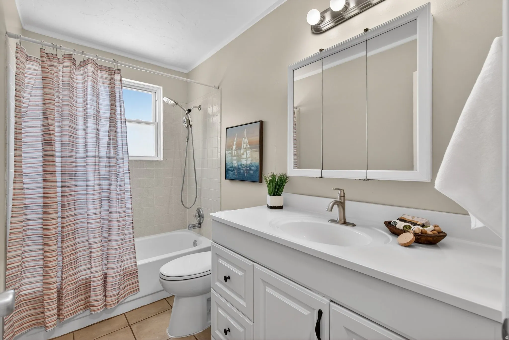 Bathroom featuring a white vanity with integrated sink, brushed nickel faucet, and a tri-fold mirrored medicine cabinet