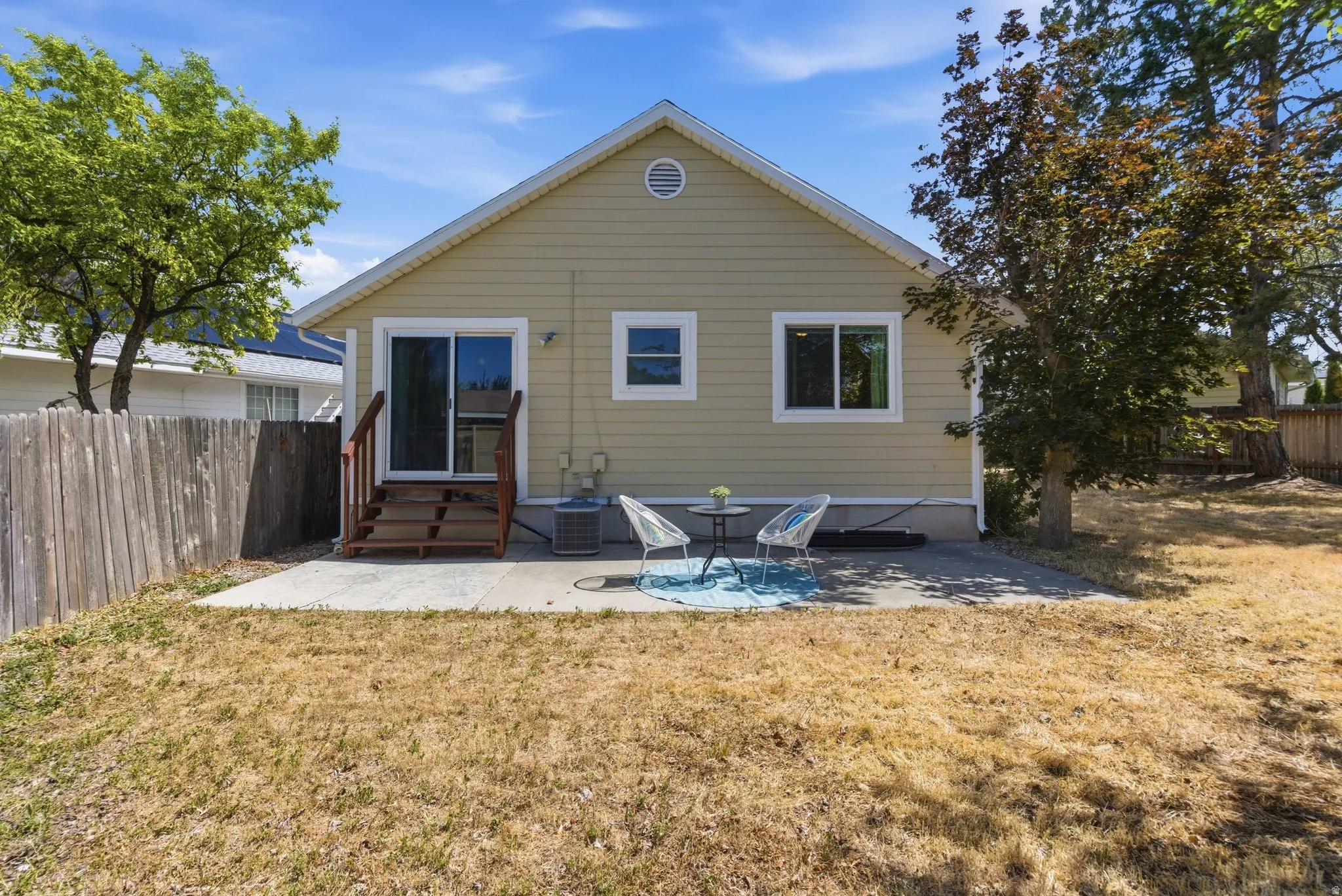 Rear exterior featuring a sliding glass door, an exterior patio, and a privacy fence
