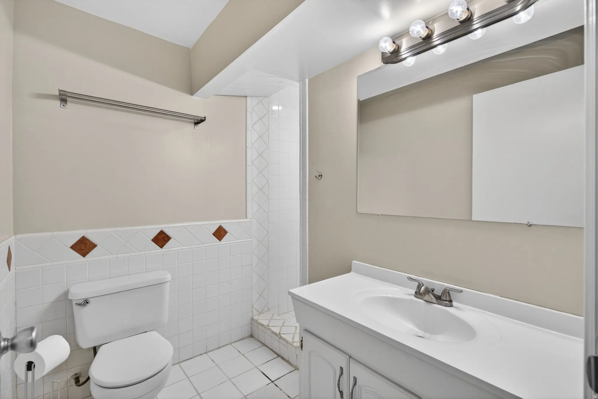 Bathroom featuring a single vanity with an integrated sink, white cabinetry, and a brushed nickel faucet