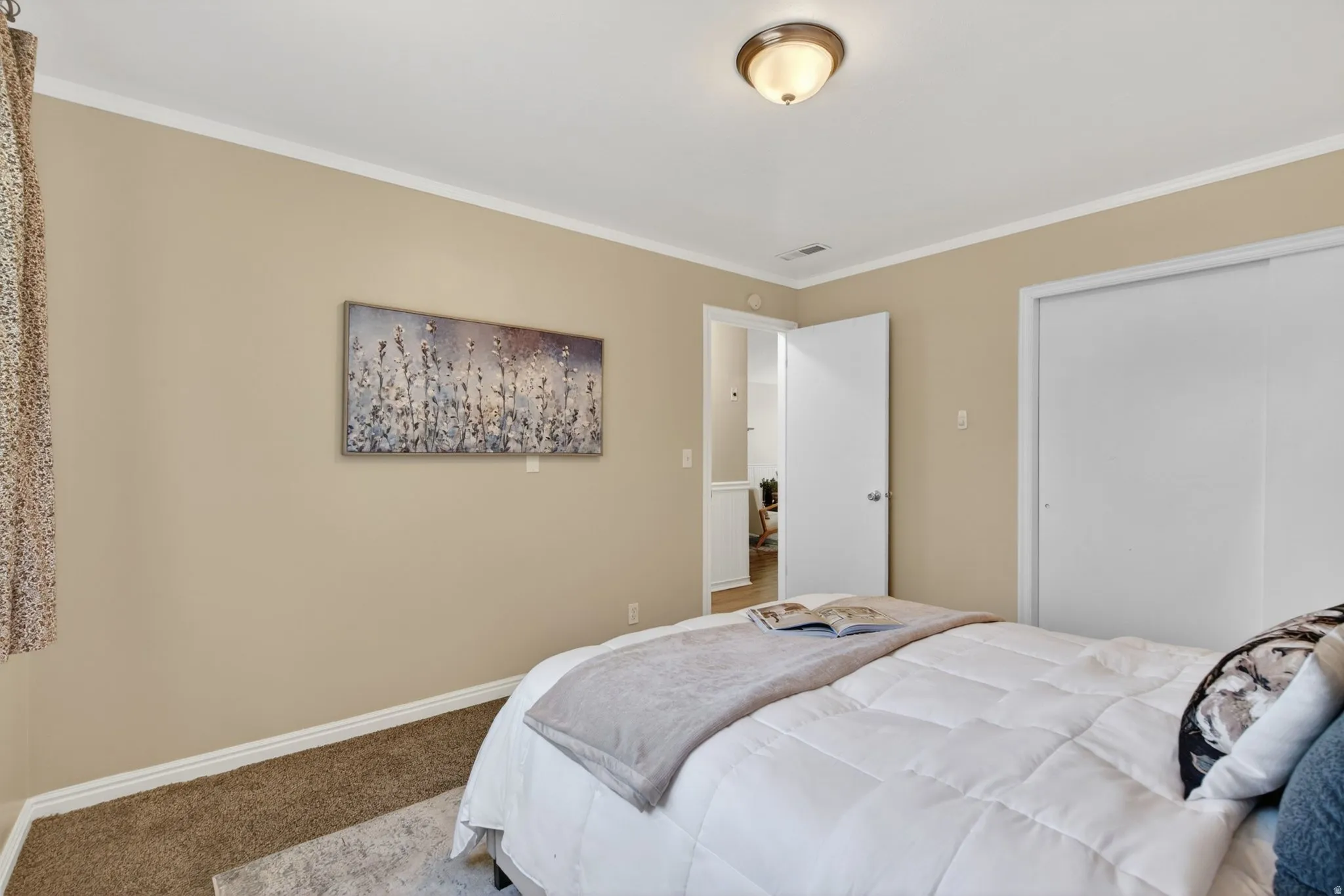 Bedroom featuring neutral paint, crown molding, a built-in closet with sliding doors, and a ceiling-mounted light fixture