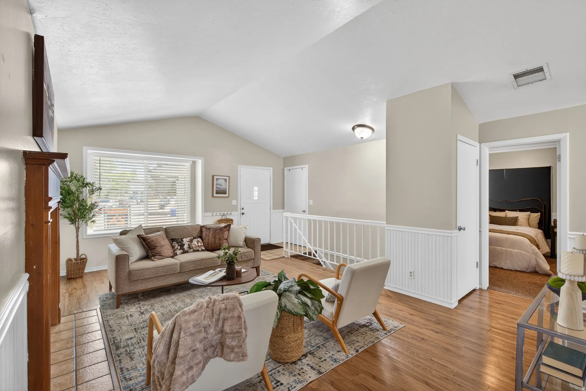Vaulted ceilings enhance this living area featuring wood-finish flooring and wainscoting details