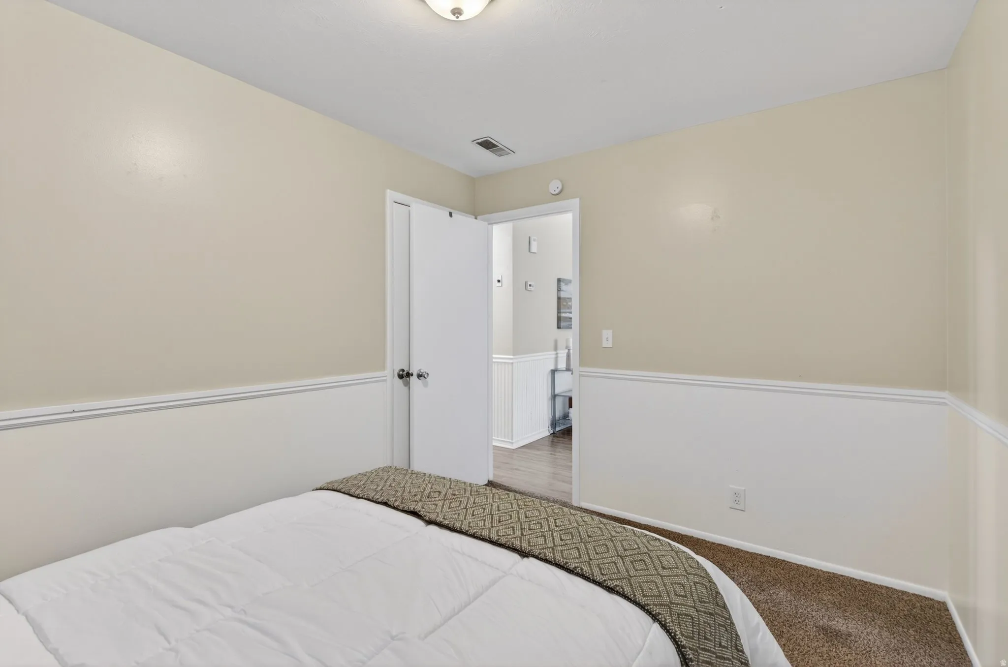 Bedroom featuring neutral-toned walls with wainscoting and carpet flooring
