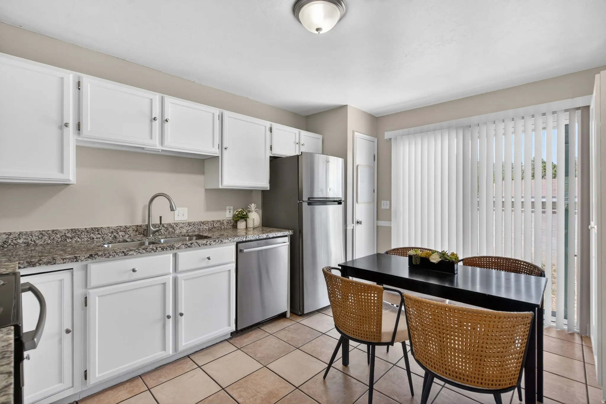 Kitchen featuring white cabinetry, granite-finish countertops, stainless steel appliances, and tile flooring