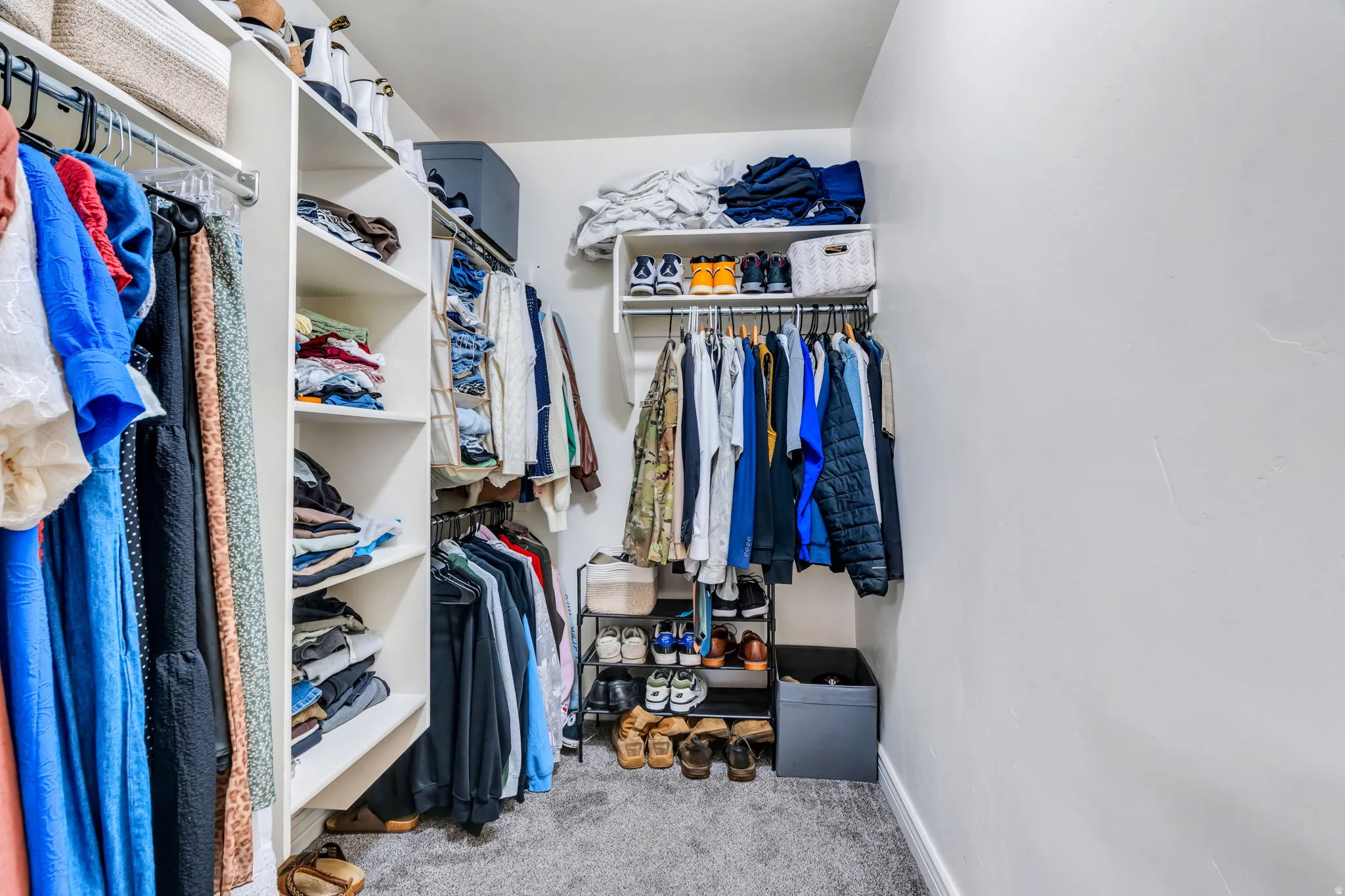 Custom closet system featuring built-in shelving, multiple hanging rods, and soft gray carpeting