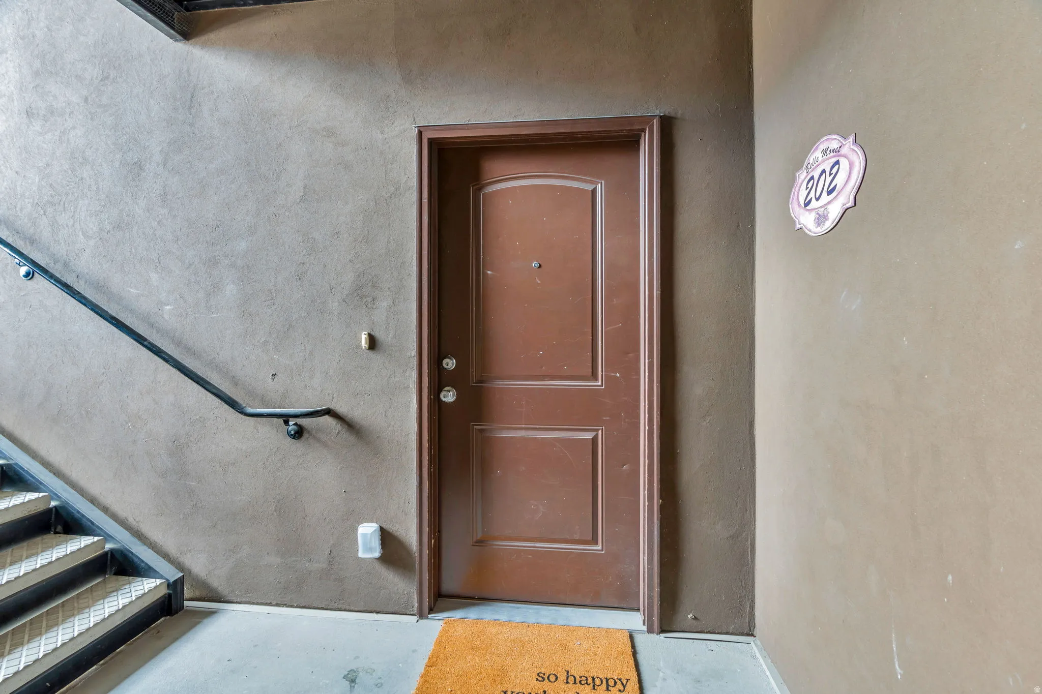 Solid panel entry door with prominent decorative trim, flanked by textured wall finishes