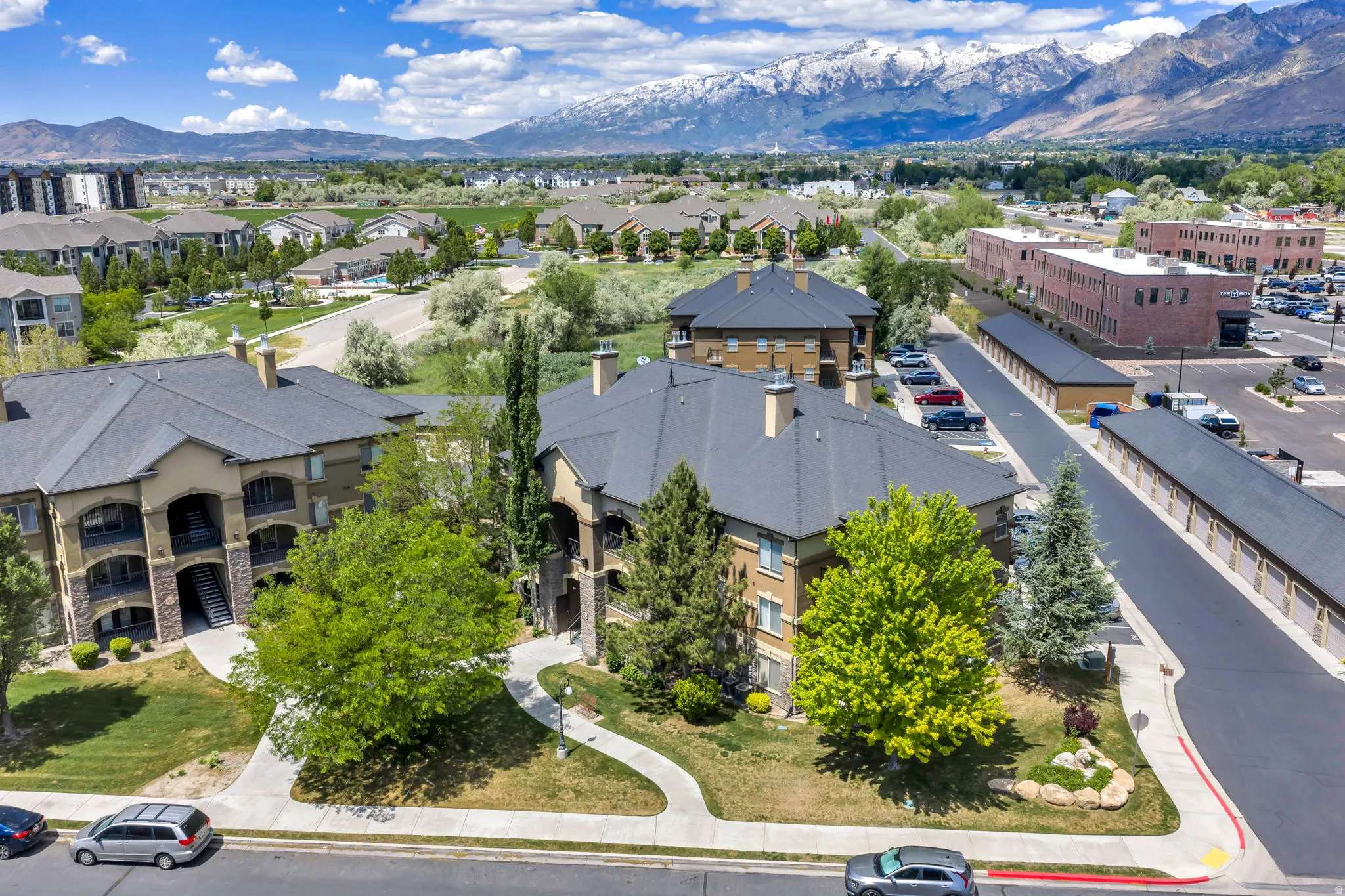 Multi-story buildings with pitched dark gray roofs and light brown stucco exteriors