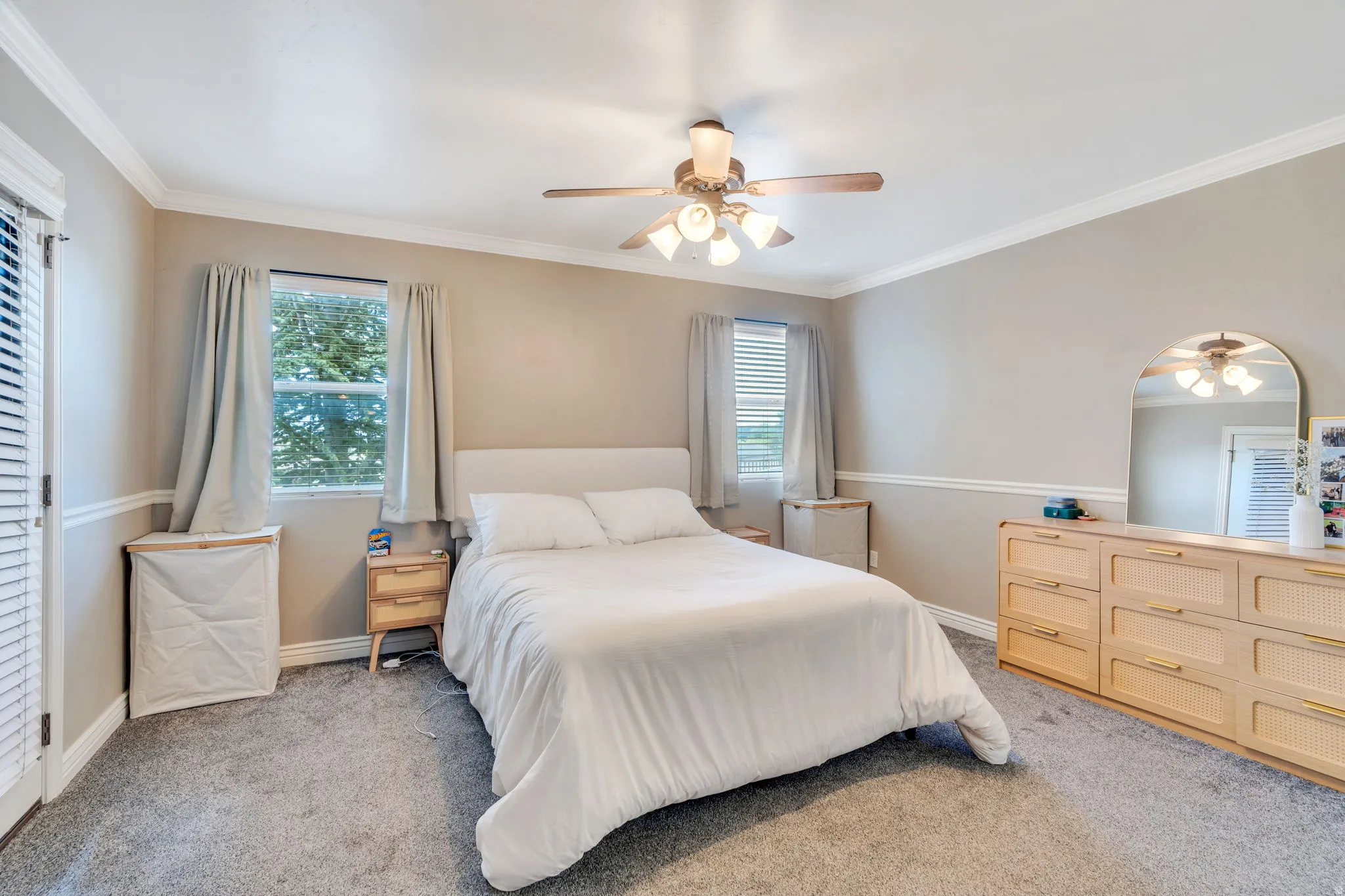 Bedroom featuring neutral wall colors, crown molding, gray carpeting, a ceiling fan with integrated lighting, and multiple windows