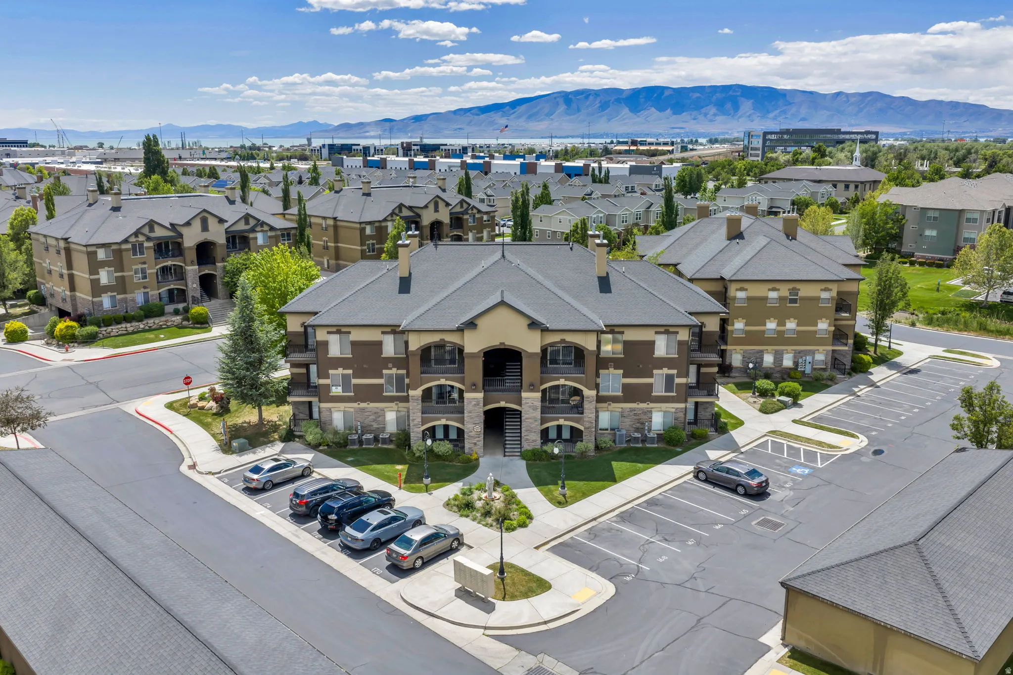 Multi-story residential building featuring a gabled roofline, stone veneer accents, and individual balconies