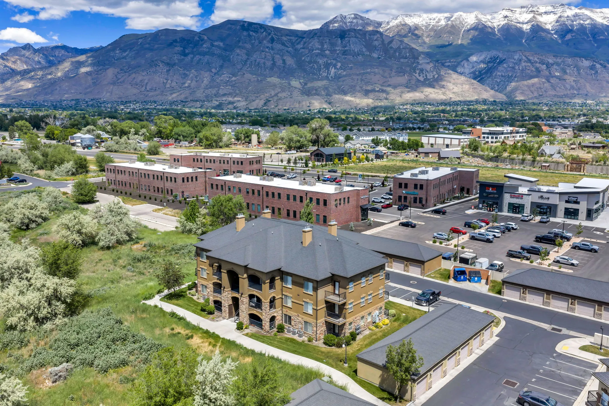 Multi-story building featuring stone and stucco exterior finishes, a dark shingle roof, and multiple balconies