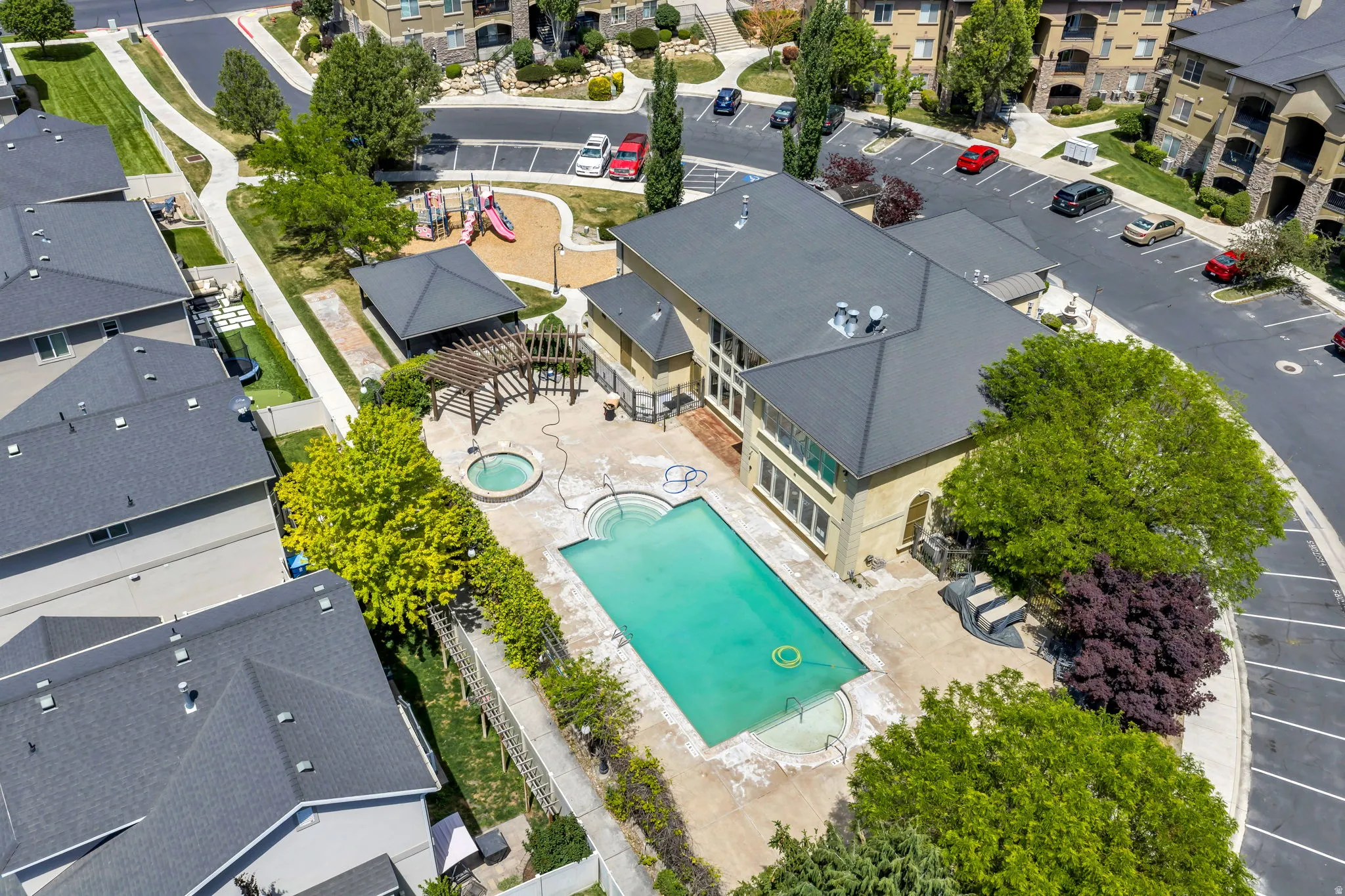 Community amenity area featuring a large swimming pool, circular spa, and a shaded pergola