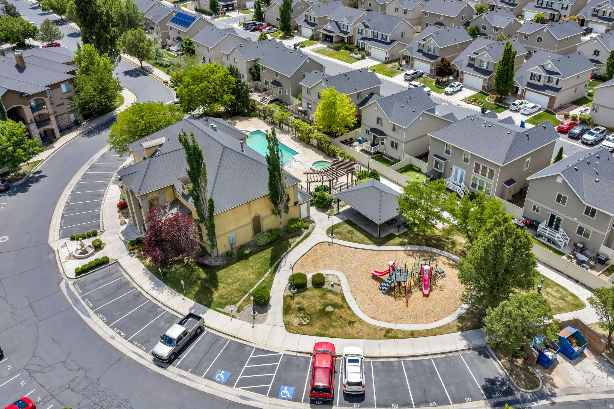 Community amenities featuring a clubhouse, outdoor swimming pool, and dedicated playground area with sand footing