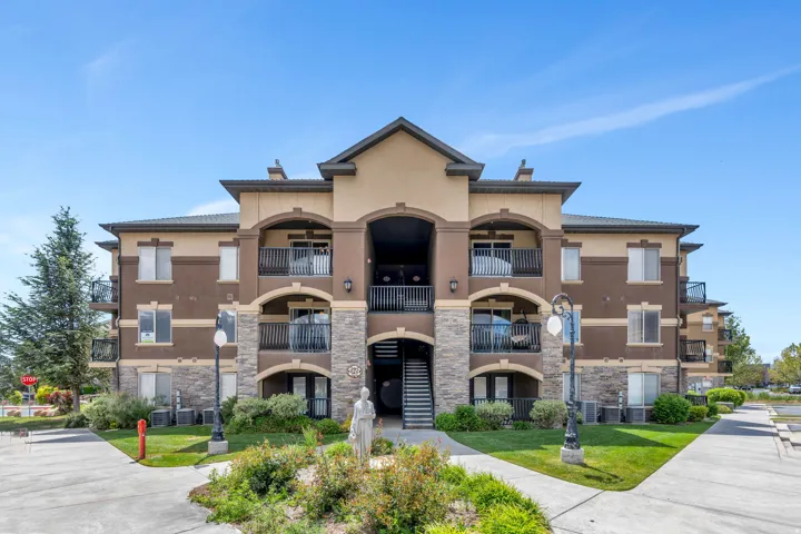 Multi-story residential building featuring a stucco and stone facade, private balconies, and a central entryway with an exterior staircase