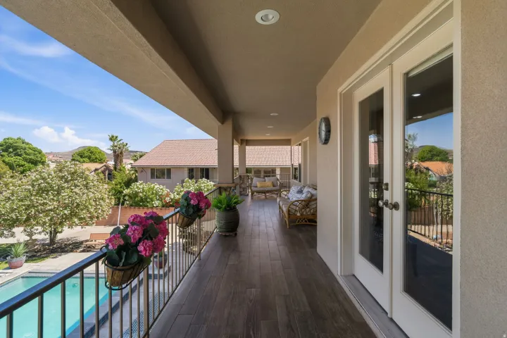 Spacious covered balcony featuring wood-finish flooring, recessed lighting, and direct access through double glass panel doors