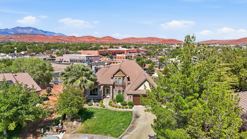 Aerial perspective showcasing a multi-level residence with a tile roof, a stone and stucco facade, and an attached garage