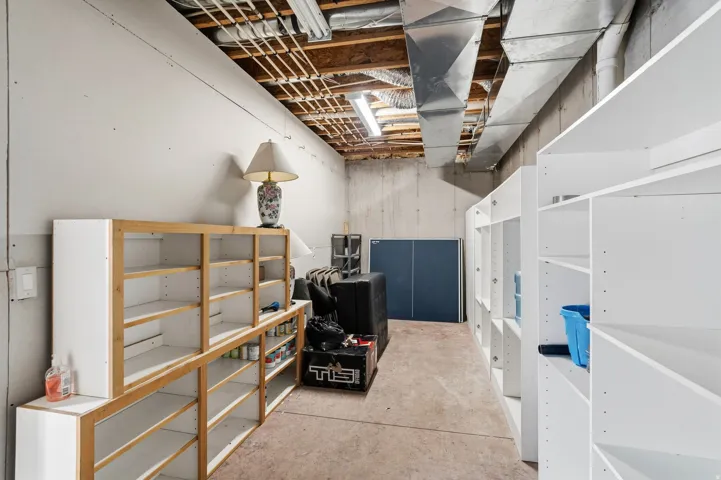 Unfinished basement area featuring exposed ceiling joists, ductwork, and concrete walls