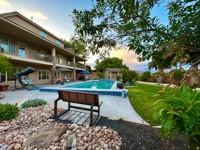 Inviting outdoor space featuring a large swimming pool, expansive concrete patio, and a manicured lawn