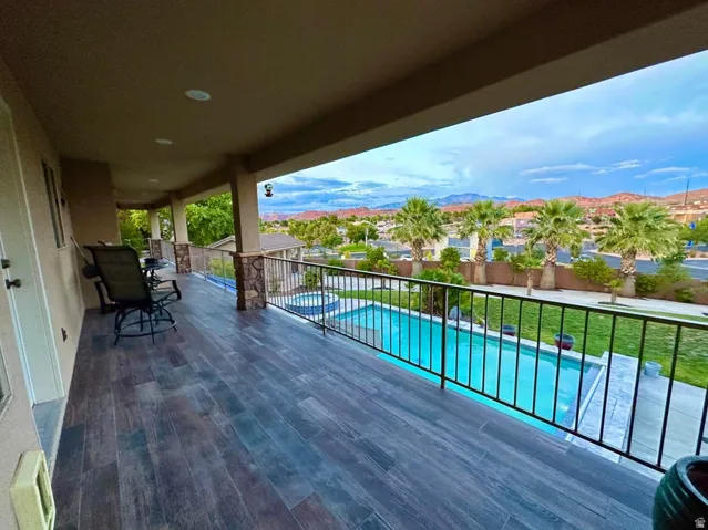 Expansive covered balcony featuring wood-finish flooring, recessed lighting, and stone-accented pillars