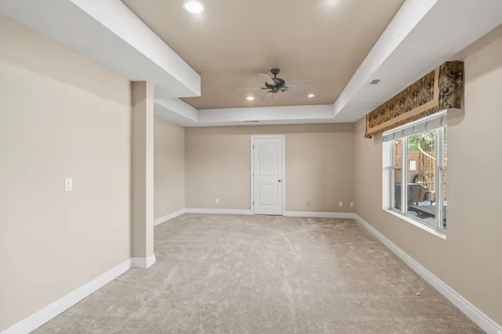 Expansive room featuring recessed lighting, a ceiling fan, tray ceiling, plush carpeting, and a white interior door