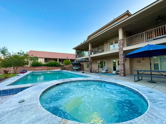Backyard oasis featuring a large swimming pool and a separate spa with tiled surrounds