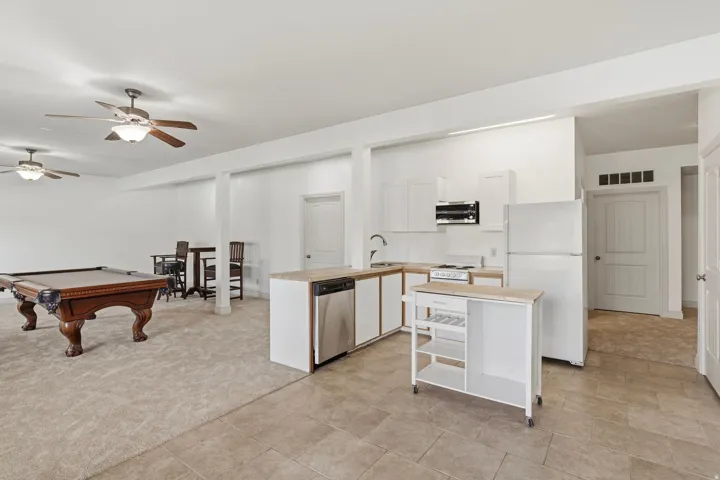 Open-concept area featuring a kitchen with white cabinetry, stainless steel dishwasher, and a refrigerator