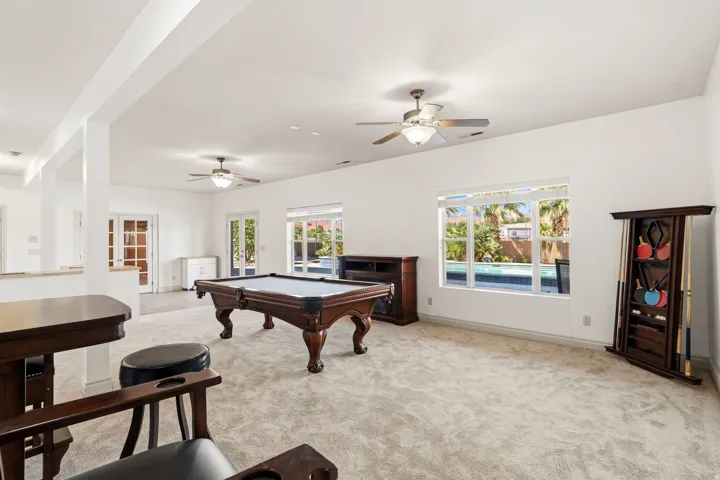 Spacious recreation room featuring light-colored carpeting and white walls
