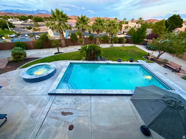 Expansive backyard featuring an in-ground swimming pool, an integrated spa, and concrete patio