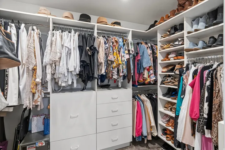 Custom closet system featuring white cabinetry and shelving