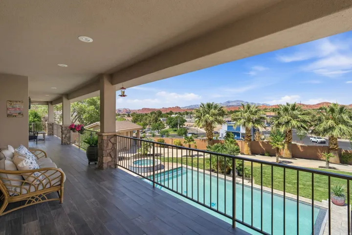 Expansive covered balcony featuring wood-finish flooring, recessed lighting, and stone-clad columns